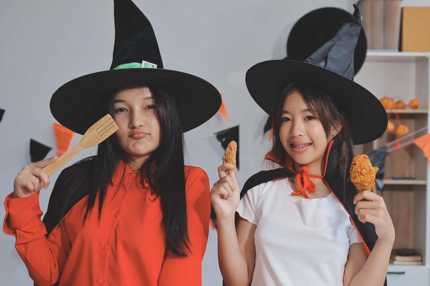 friendship, holiday and people concept - group of happy smiling friends in halloween costumes of vampire, devil, witch and cheetah at home party photo