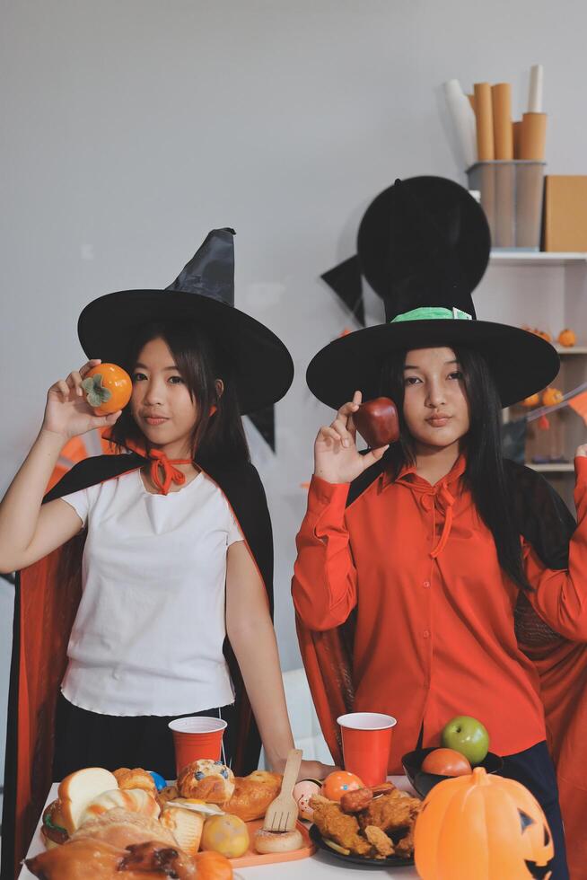 friendship, holiday and people concept - group of happy smiling friends in halloween costumes of vampire, devil, witch and cheetah at home party photo
