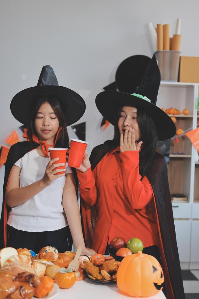 friendship, holiday and people concept - group of happy smiling friends in halloween costumes of vampire, devil, witch and cheetah at home party photo