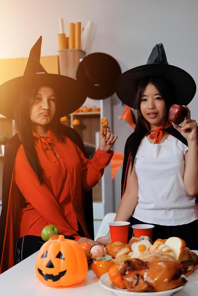 friendship, holiday and people concept - group of happy smiling friends in halloween costumes of vampire, devil, witch and cheetah at home party photo
