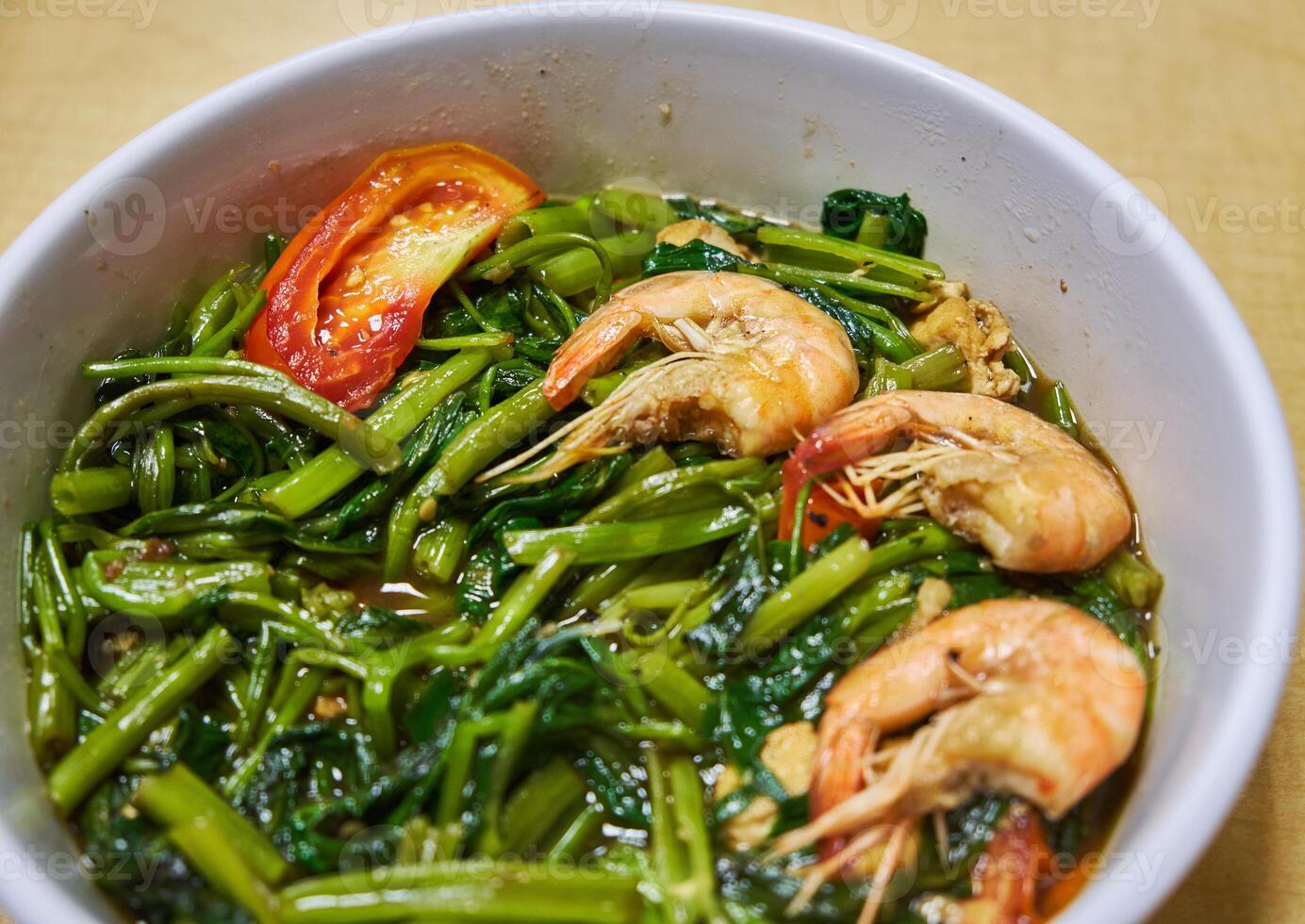 Close up of stir-fry water spinach on white bowl on wooden background, green vegetables with shrimps photo