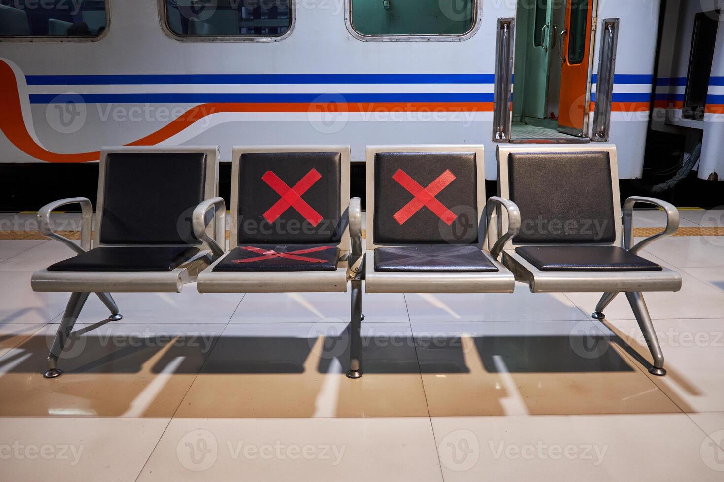 Row of seats with physical distancing signs in the Pasar Senen train station, Jakarta. Seats in the platform of train station with social distancing signs photo