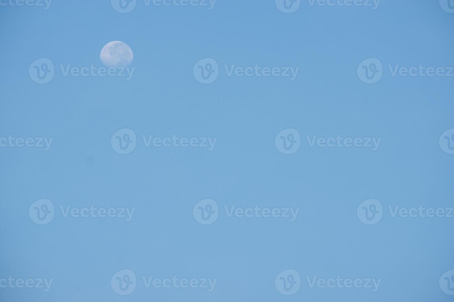 Moon in the bright blue sky with negative space photo