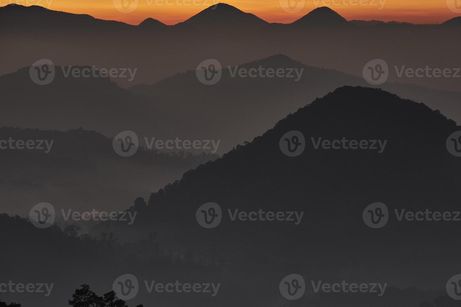 Silhouette of mountains and hills with fog and orange sky from the top of mountain in the sunrise photo
