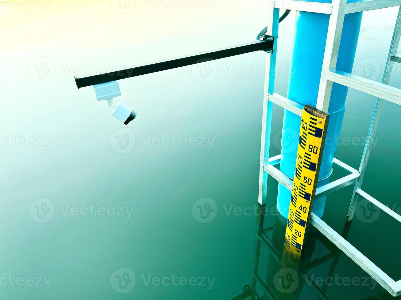 water level gauge at a reservoir, featuring a yellow measurement scale and a camera sensor to monitor water levels, monitoring equipment provide a clear visual of technology, hydrological studies photo