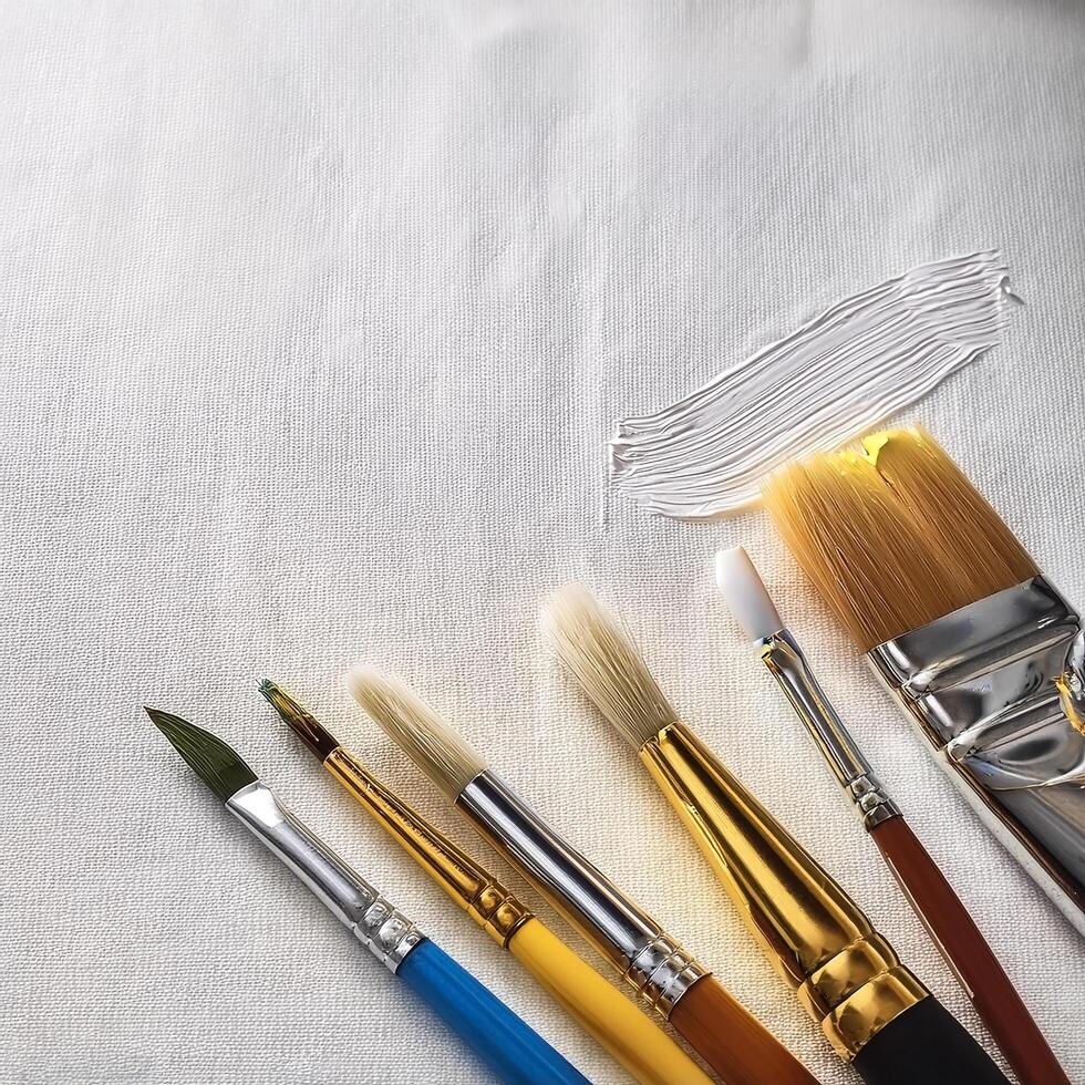 Paint and brushes lie on a white canvas. Creative Activities photo