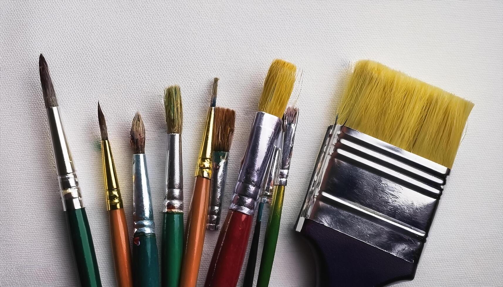 Paint and brushes lie on a white canvas. Creative Activities photo