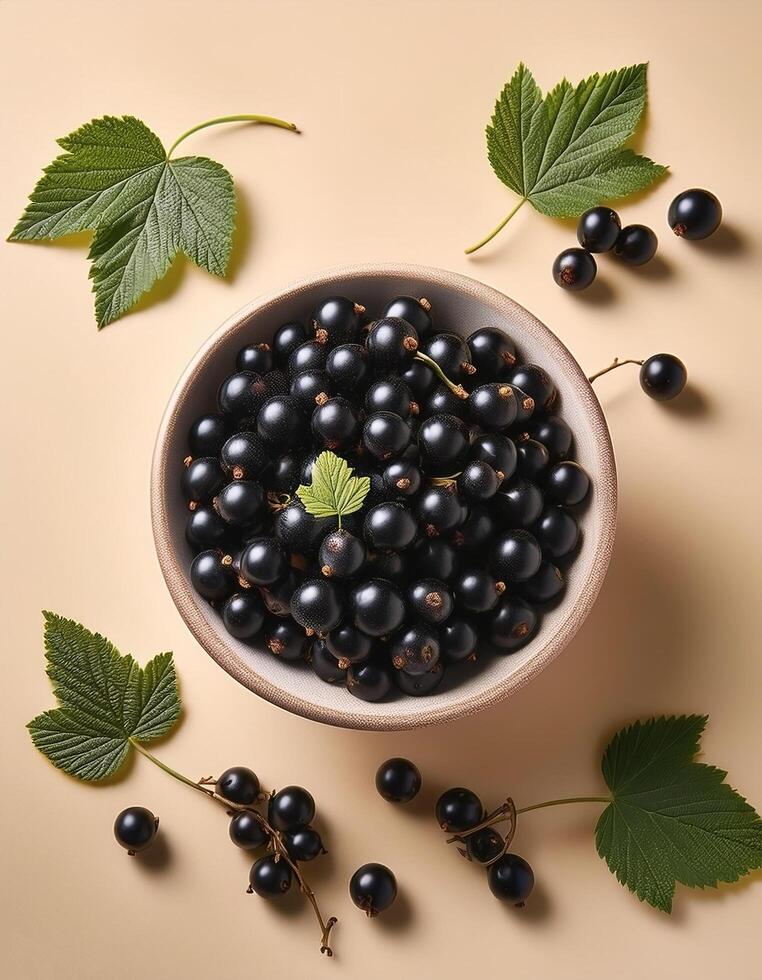 Black currants in a bowl, surrounded on a beige background photo