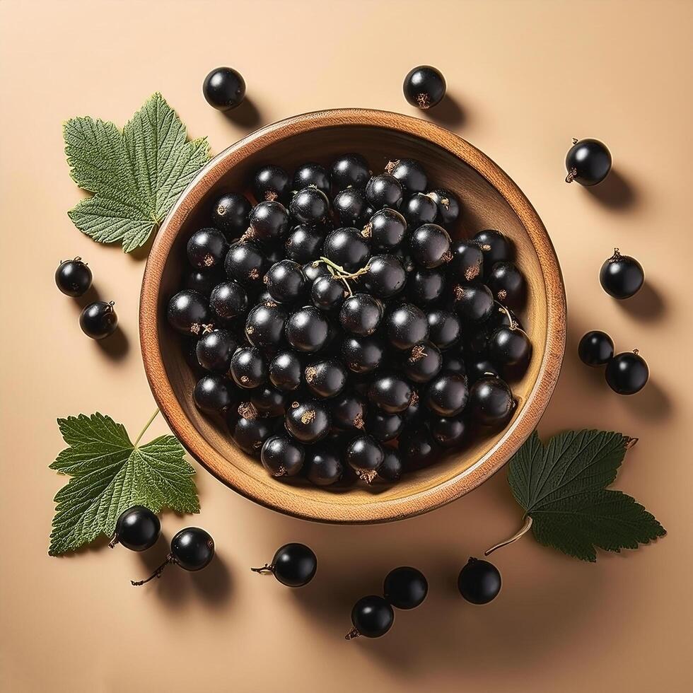 Black currants in a bowl, surrounded on a beige background photo