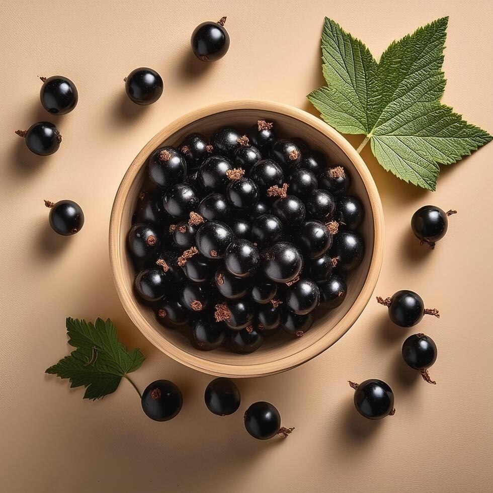Black currants in a bowl, surrounded on a beige background photo