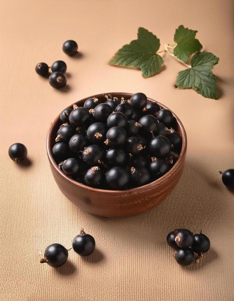 Black currants in a bowl, surrounded on a beige background photo