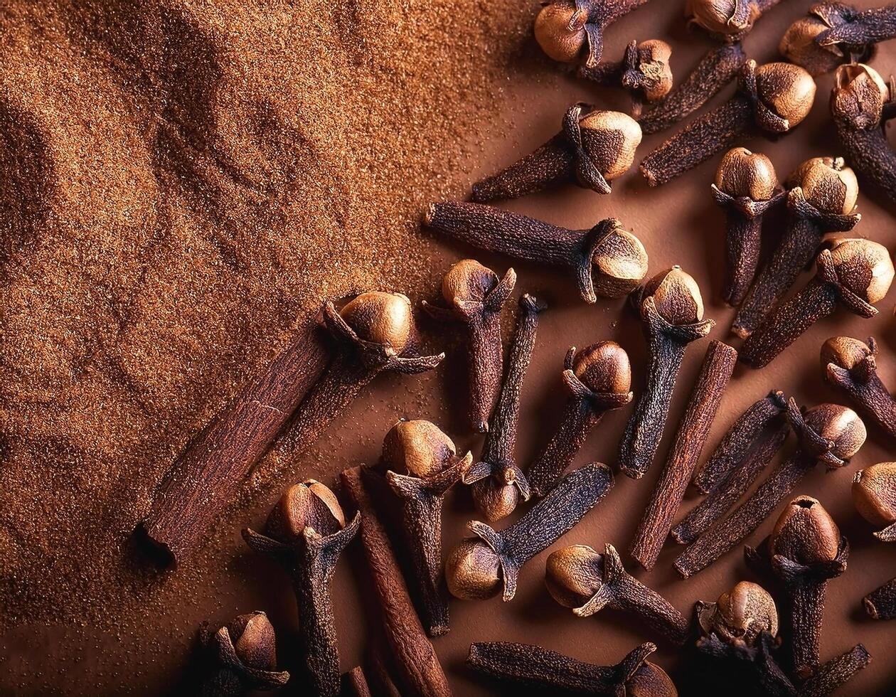 Cloves and cinnamon are spread on a brown background photo
