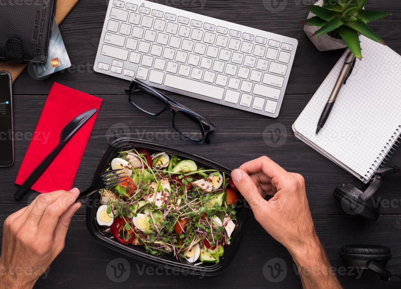 Having lunch at workplace. Businessman enjoying healthy salad at work desk, top view photo
