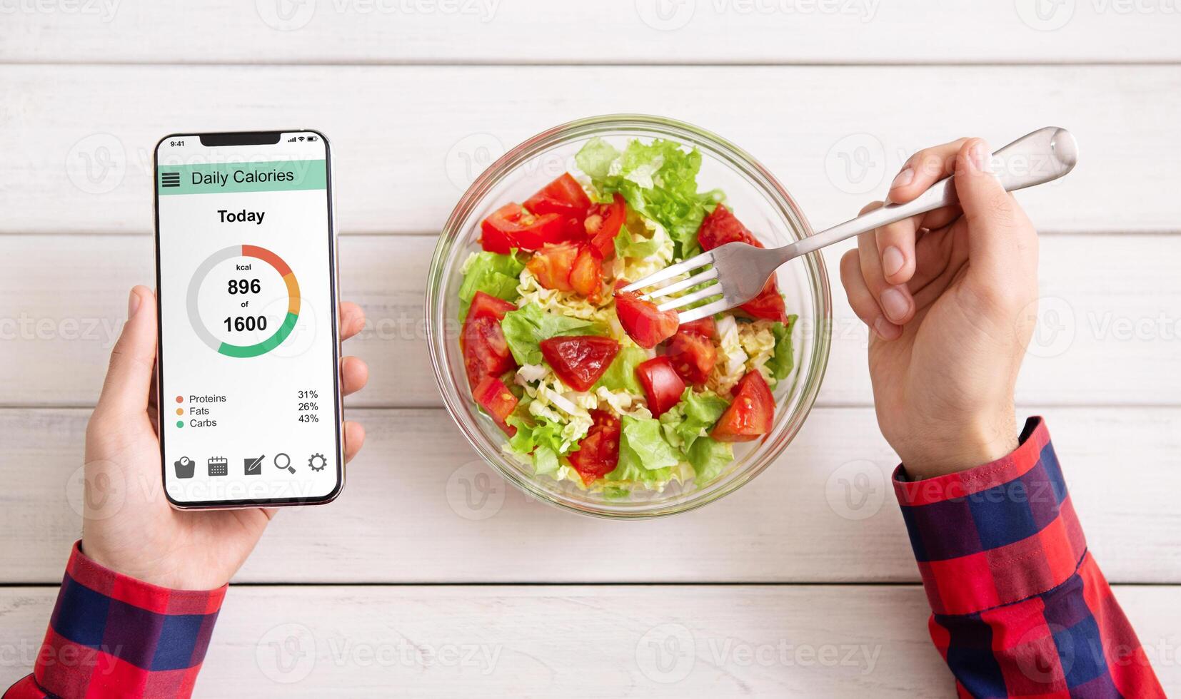 Smart eating and diet planning concept. Man eating vegetable salad and counting calories on mobile application, top view photo