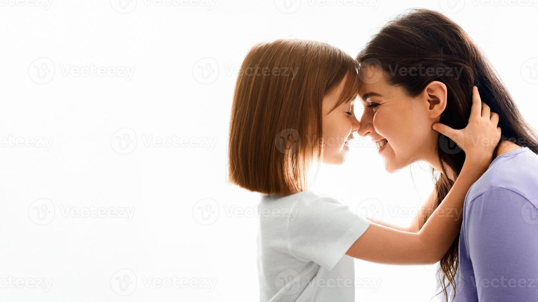 Close up of sweet pretty daughter cuddling with her young mother, white background, free space photo