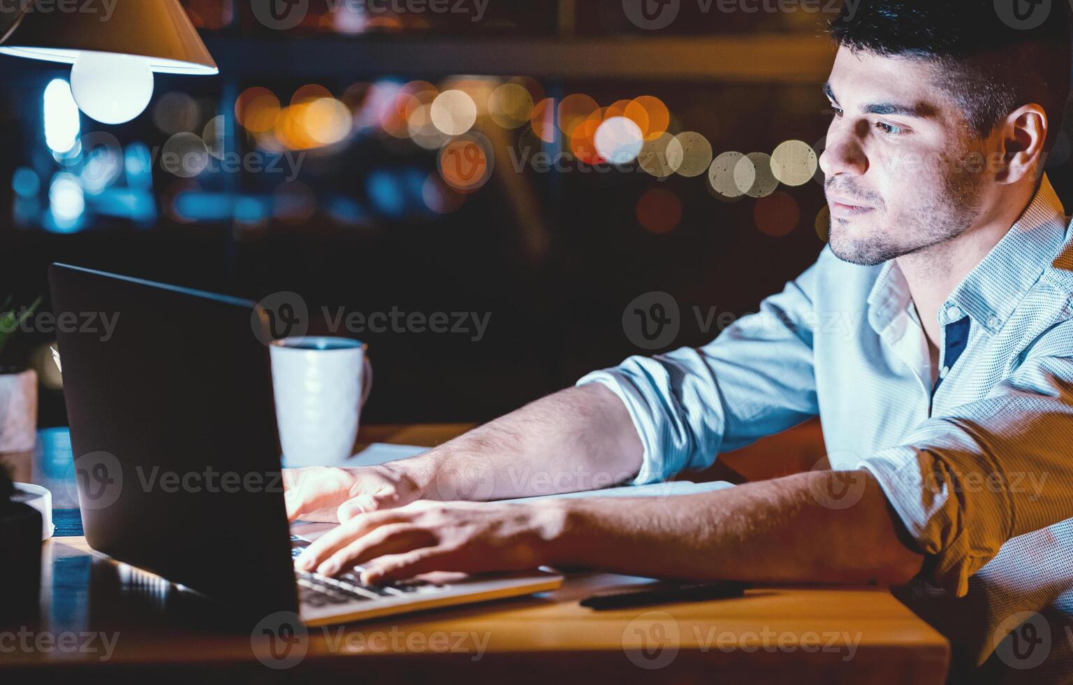 Workaholism. Businessman Working On Laptop Computer Typing Financial Business Report Late At Night At Workplace photo