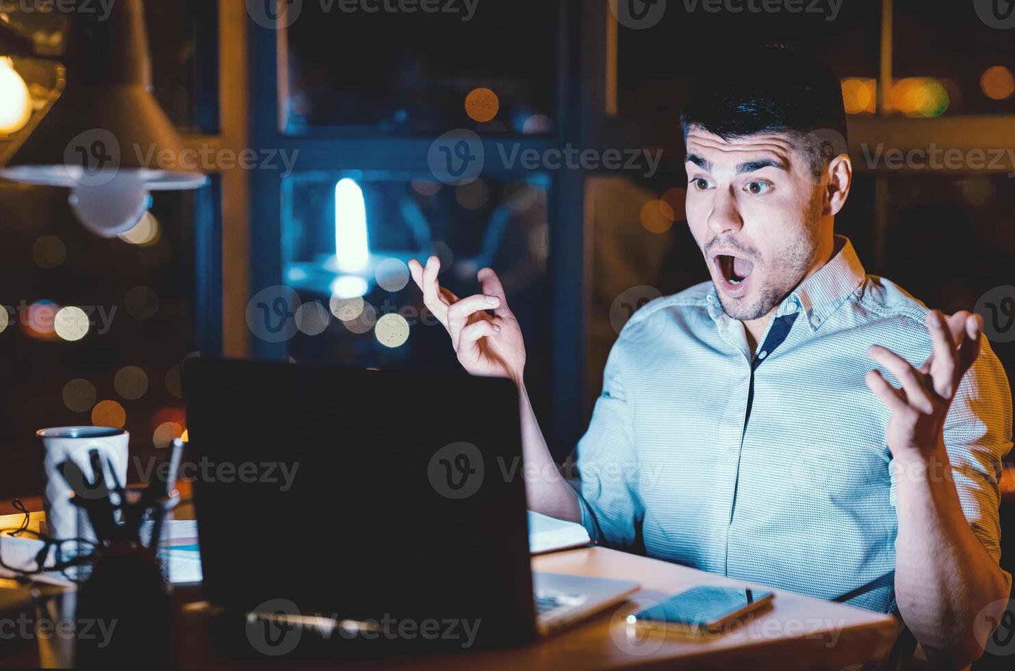 Shocked Businessman With Open Mouth Looking At Laptop Having Unexpected Problem Working In Modern Office At Night photo