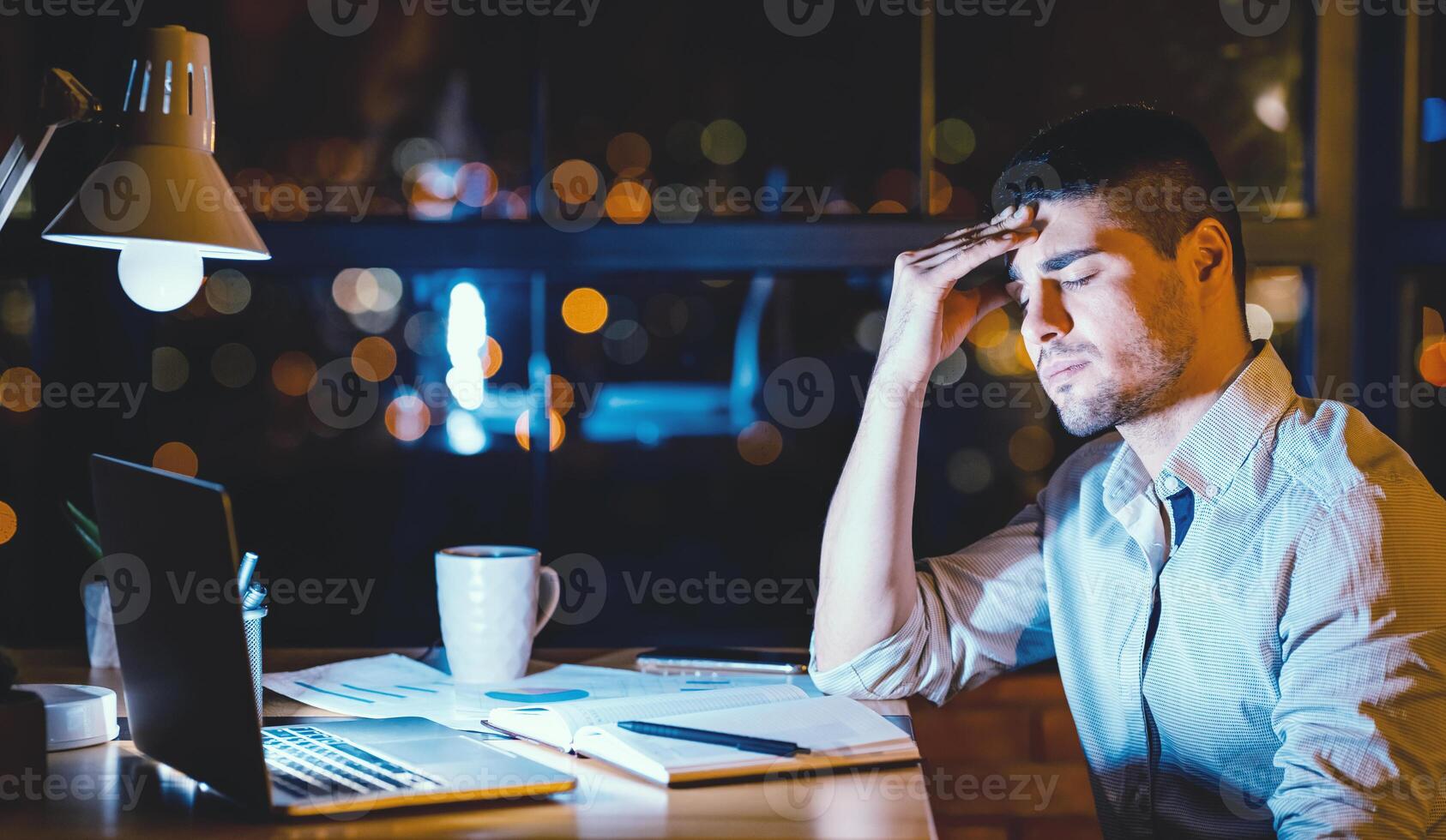 Headache. Tired Manager Man At Laptop Touching Forehead Working Late At Night In Modern Office. Copy Space photo