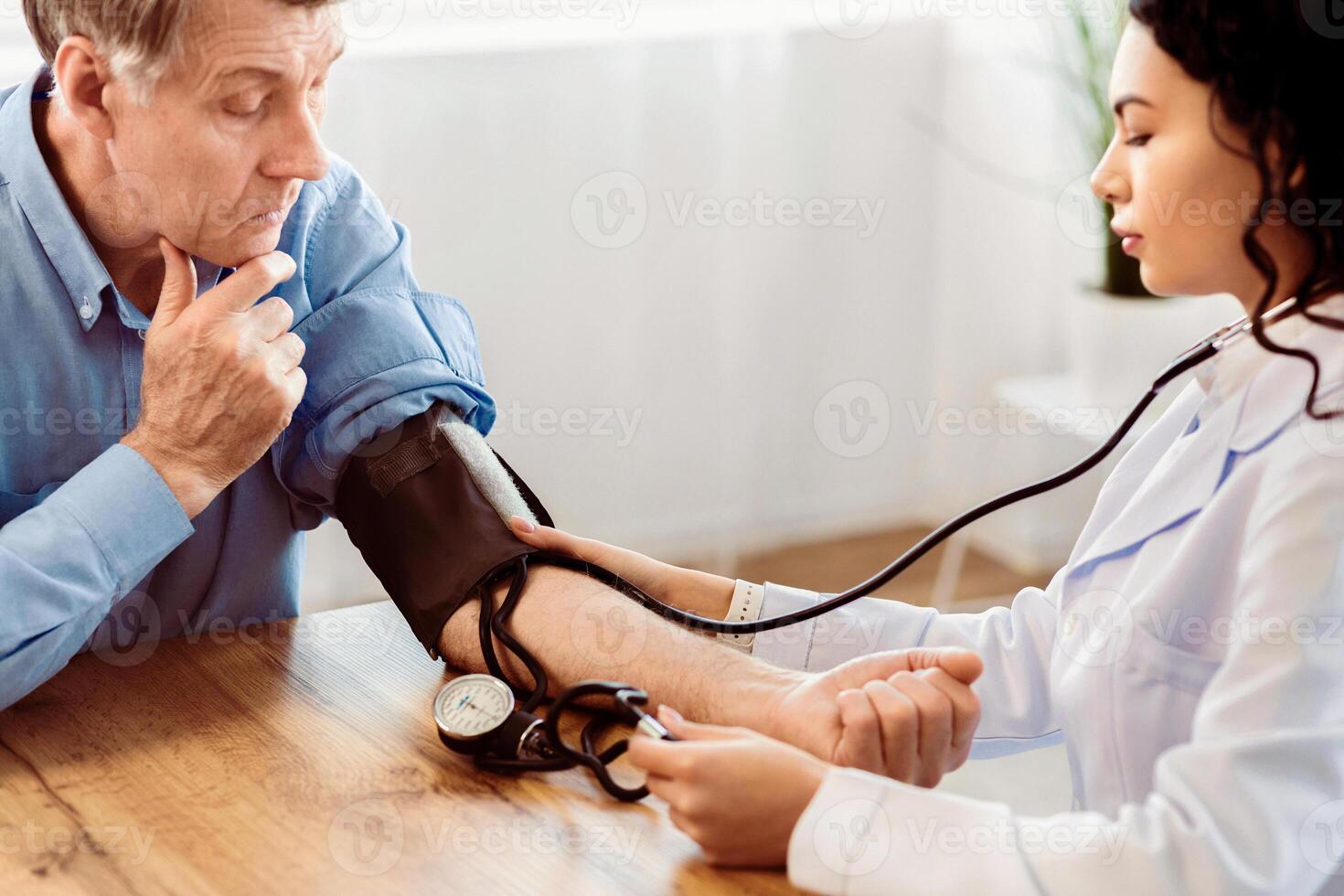 Cardiology. Mexican doctor measuring blood pressure of senior man, checking patient, free space photo