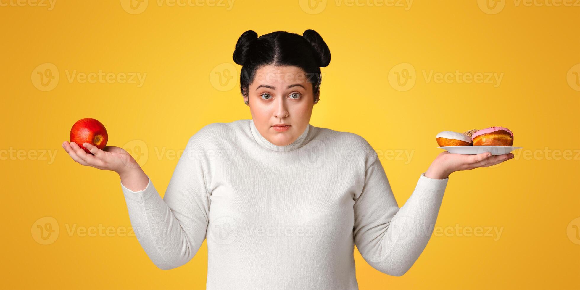 Confused Plus Size Girl Holding Apple And Donuts, Choosing Between Healthy And Unhealthy Junk Food, Yellow Background, Panorama photo