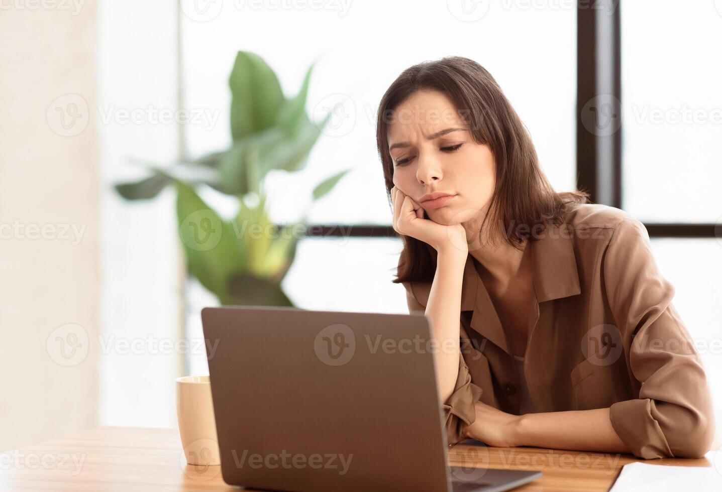 Overworked Person. Bored girl using laptop sitting at table in contemporary office, free space photo