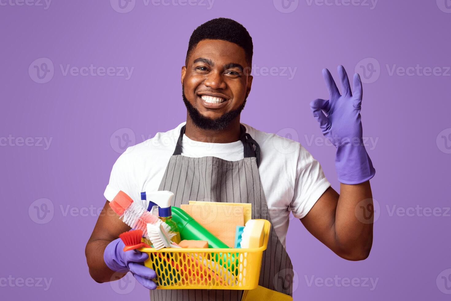Easy Cleaning. Smiling African Man Holding Basket With Detergents And Household Supplies And Showing Ok Gesture On Pink Background, Copy Space photo