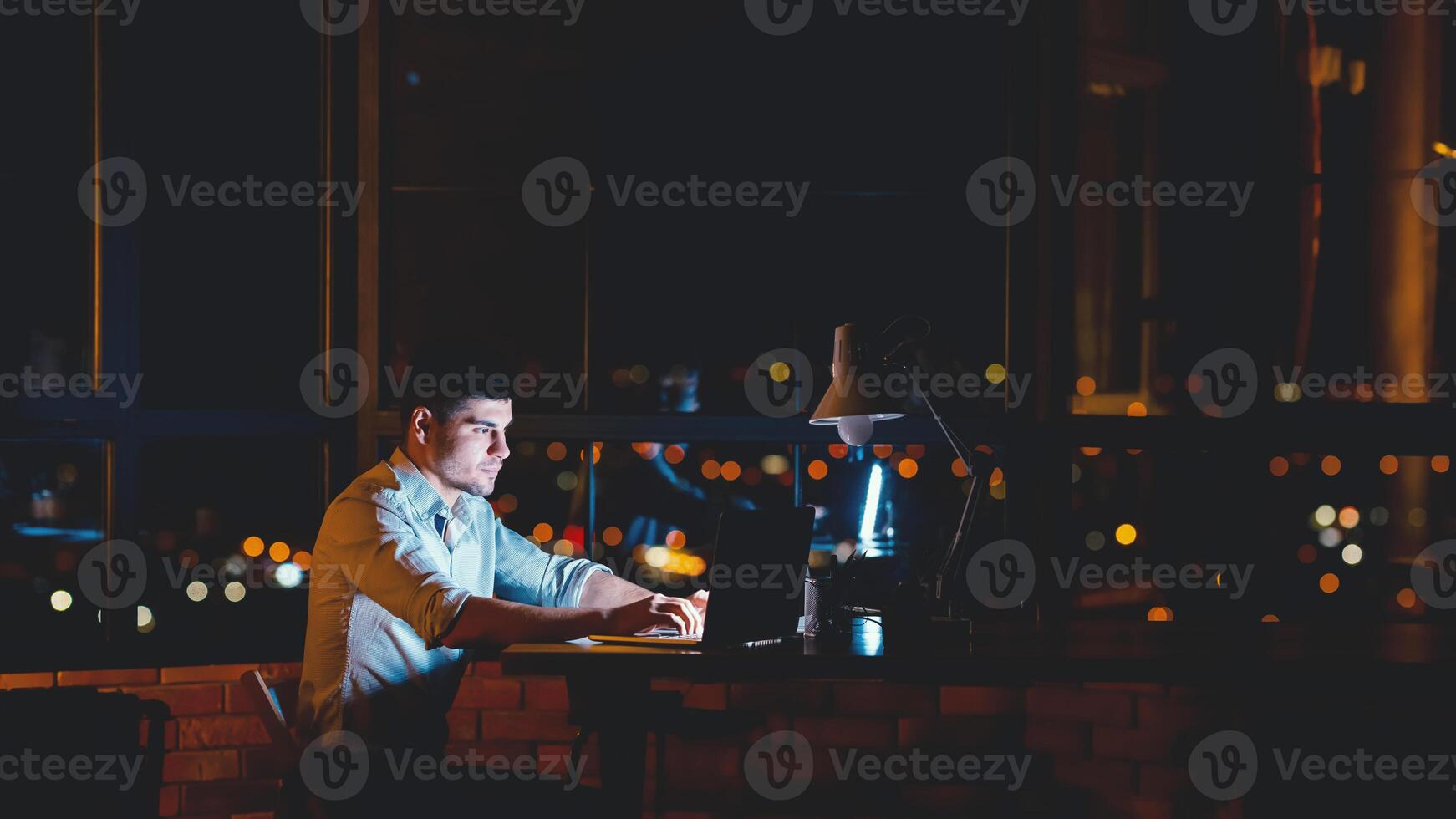 Business Man Working On Laptop Computer Sitting In Modern Office At Night. Panorama With Copy Space photo