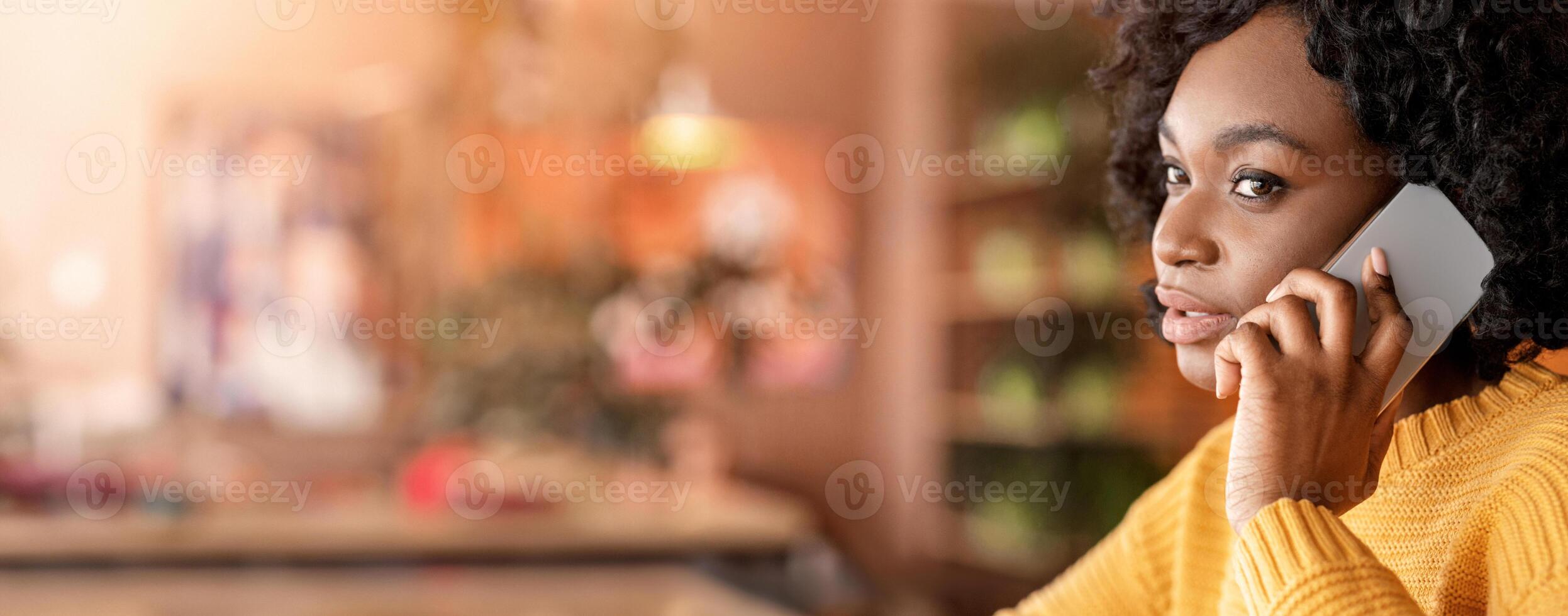 Close up profile photo of black woman talking on mobile phone, cafe interior, free space