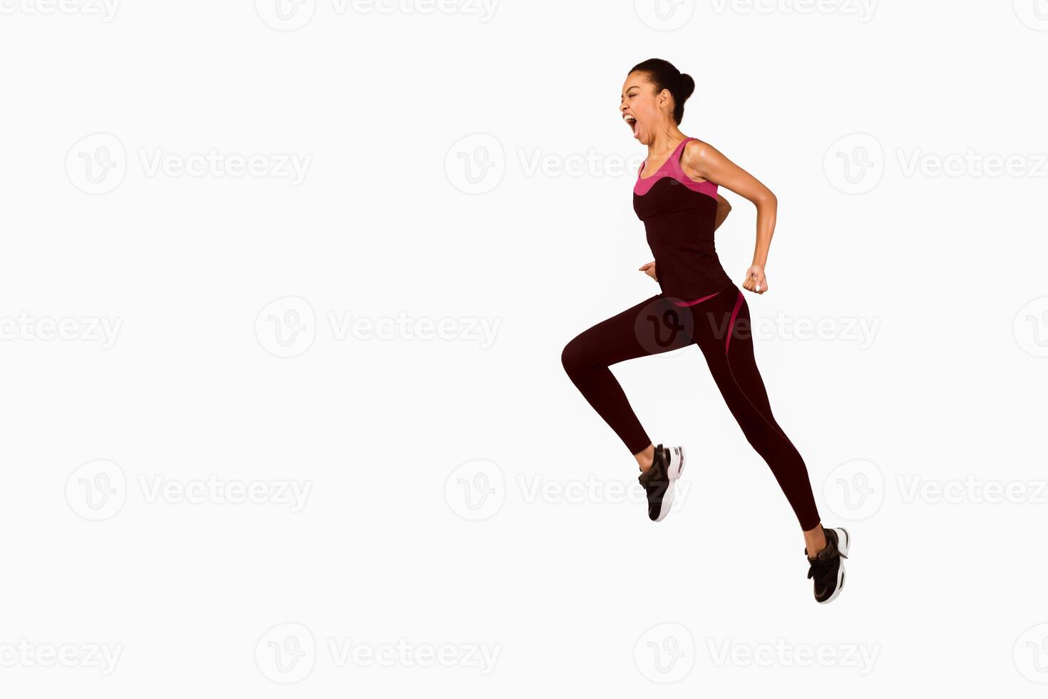 Emotional Afro Woman Jumping And Shouting During Workout Over White Studio Background. Motivation In Sport. Full Length, Copy Space photo