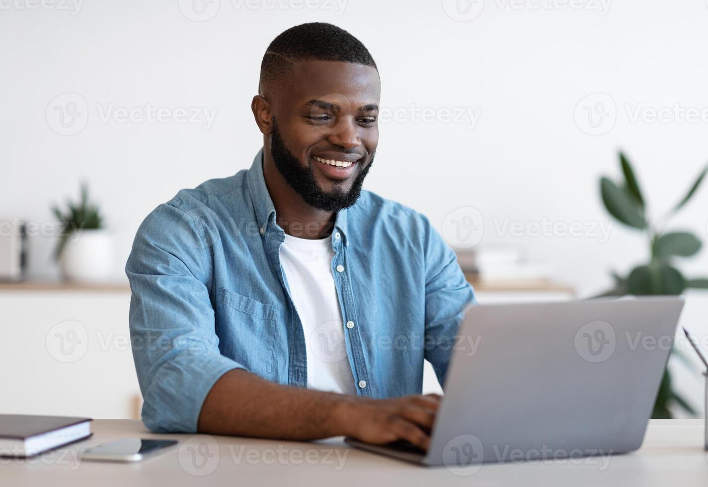 Remote Work. Handsome Black Freelancer Guy Working On Laptop At Home Office, Sitting At Desk With Computer, Smiling African American Man Looking At Device Screen, Enjoying Freelance Job, Copy Space photo