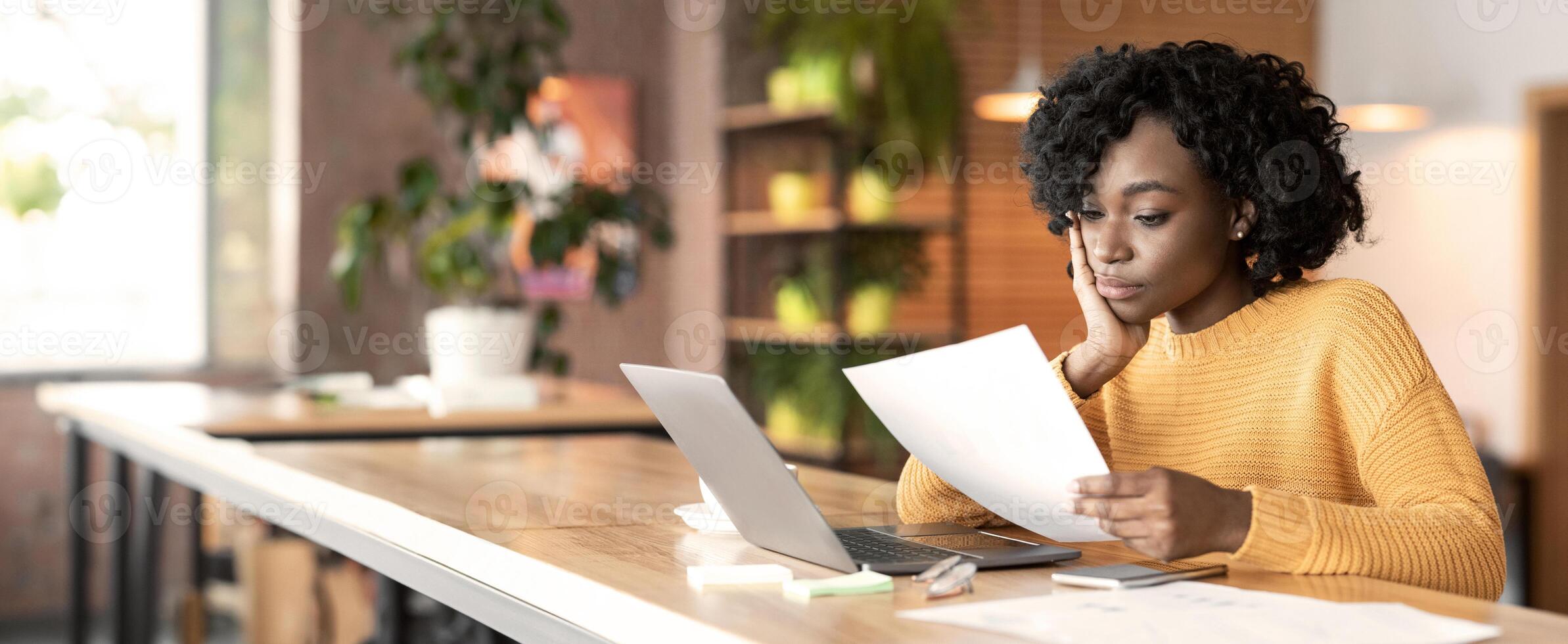 Concentrated afro girl professional editor working with text at cafe, using laptop, empty space photo