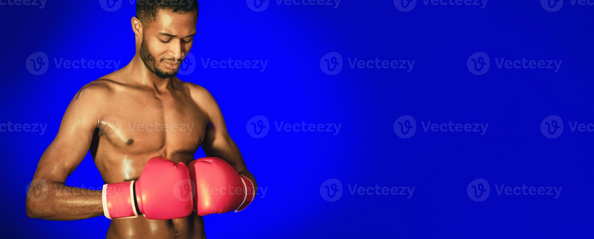 Boxing Training. African American Boxer Man Wearing Gloves Preparing For Fight Standing On Blue Background In Studio. Free Space photo