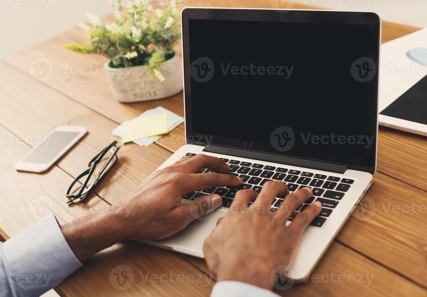 Unrecognizable african-american businessman working on laptop in modern office, side view, copy space photo