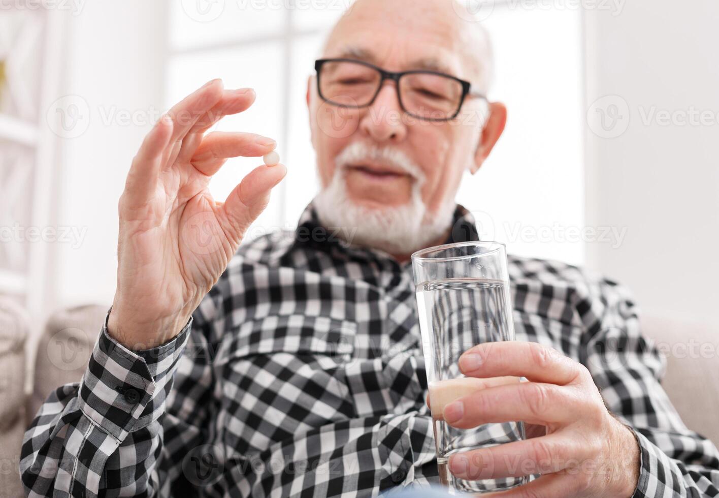 Old man taking pills with water glass. Healthcare, treatment, aging concept photo