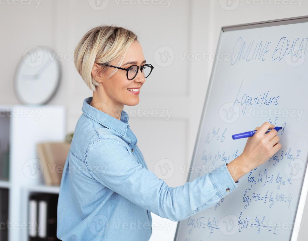 Experienced college lecturer teaching advanced mathematics online, writing down complicated problem on blackboard. University math professor explaining new material to students photo