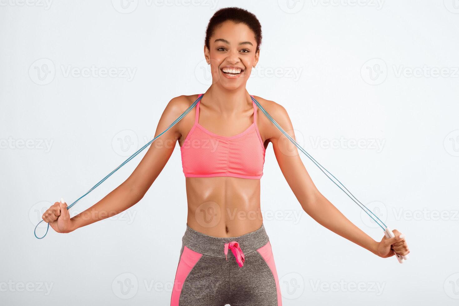 Fitness Concept. Happy African American Woman Holding Jump Rope Smiling Posing Over Pink Background. Studio Shot photo