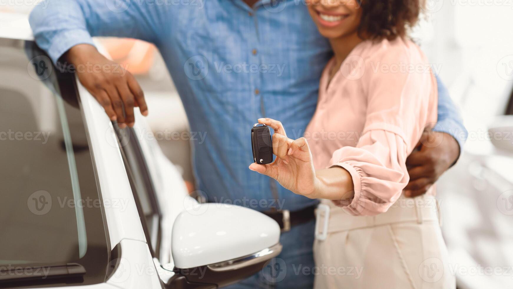 Buying Automobile. Unrecognizable Couple Showing New Car Key Hugging Standing In Dealership Shop. Panorama, Cropped, Shallow Depth photo