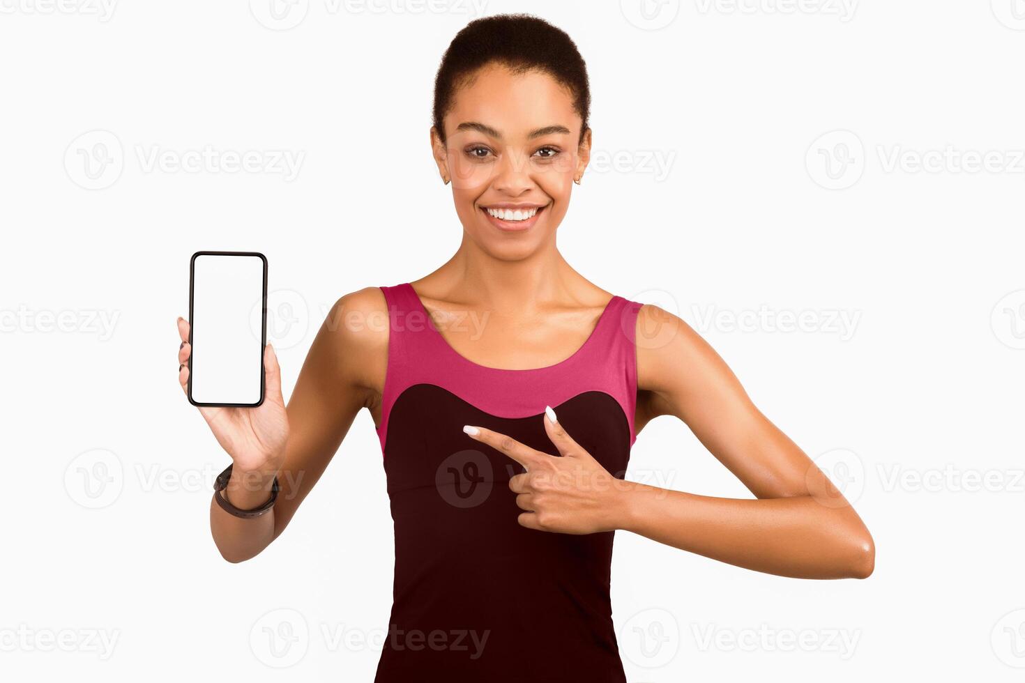 Fitness Application. African American Girl Pointing Finger At Smartphone Blank Screen Smiling At Camera Standing On White Background. Mockup photo
