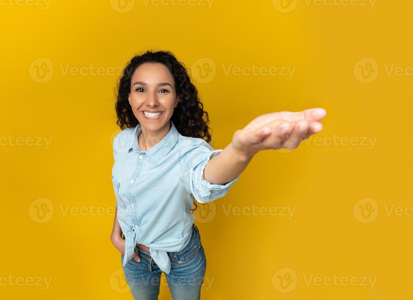 Excited young woman outstretching cupped hand, trying to hold something invisible on her palm, giving it away or asking for something, orange yellow wall, copy space, above top high angle view photo