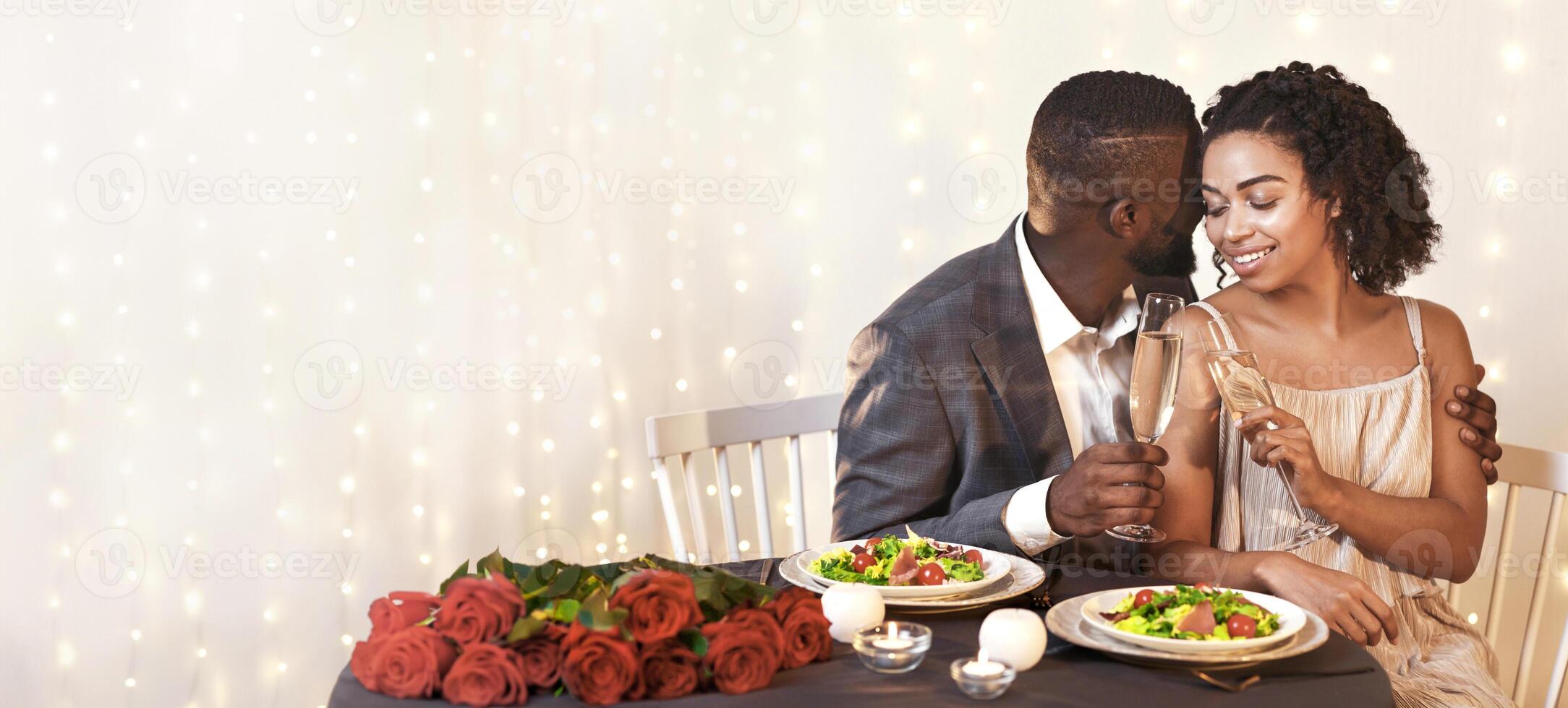 Romantic black couple toasting with champagne while having dinner at restaurant, copy space photo