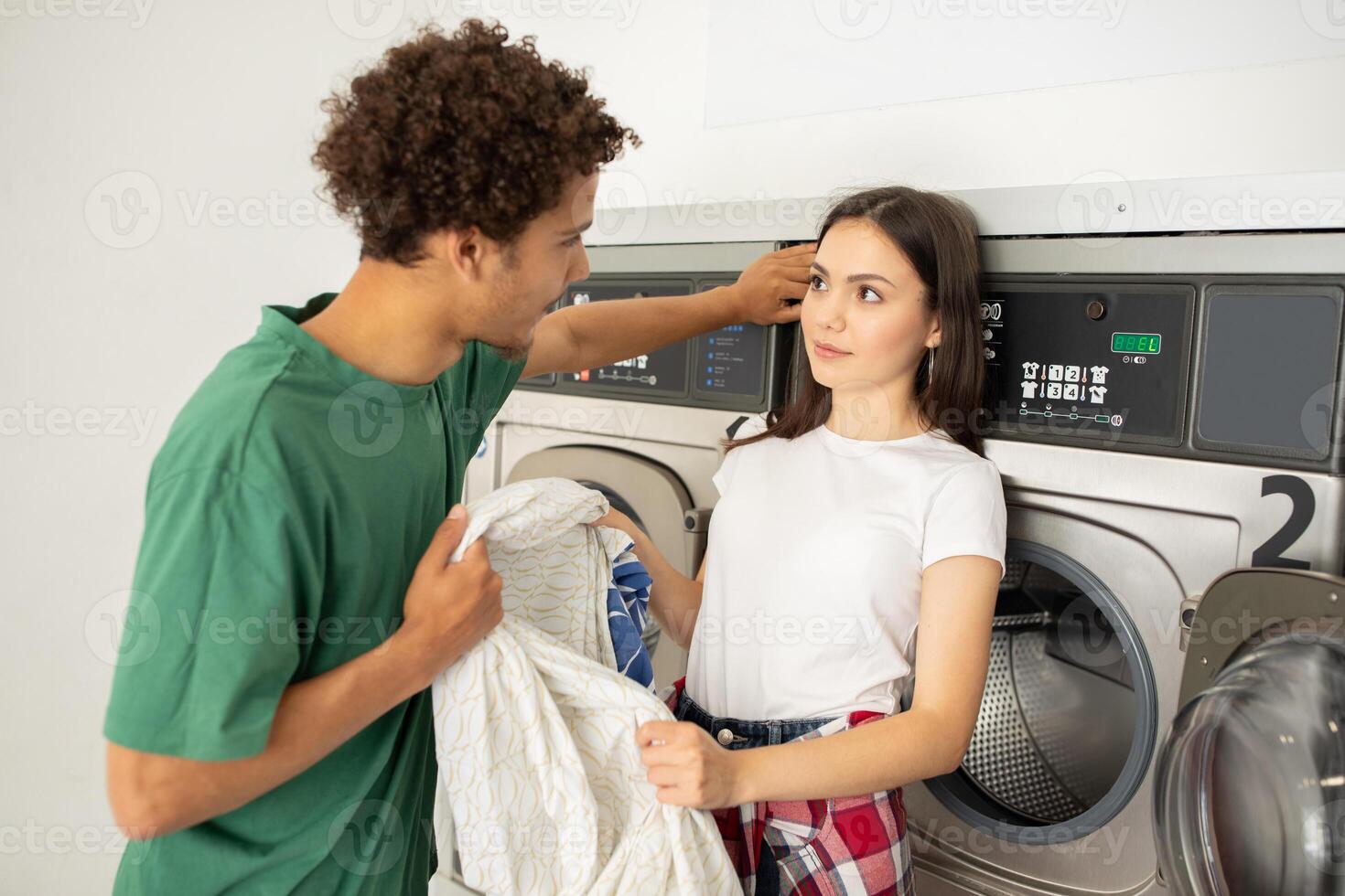 A young man and woman engage in playful banter while doing laundry at a laundromat. The ambience is casual, with machines running in the background as they enjoy each other's company. photo