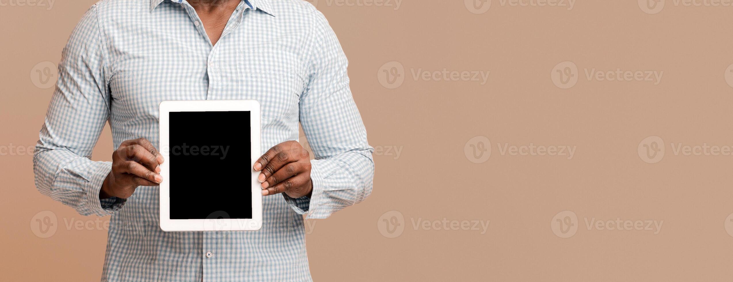Modern digital tablet with blank screen in hands of african american man, empty space photo