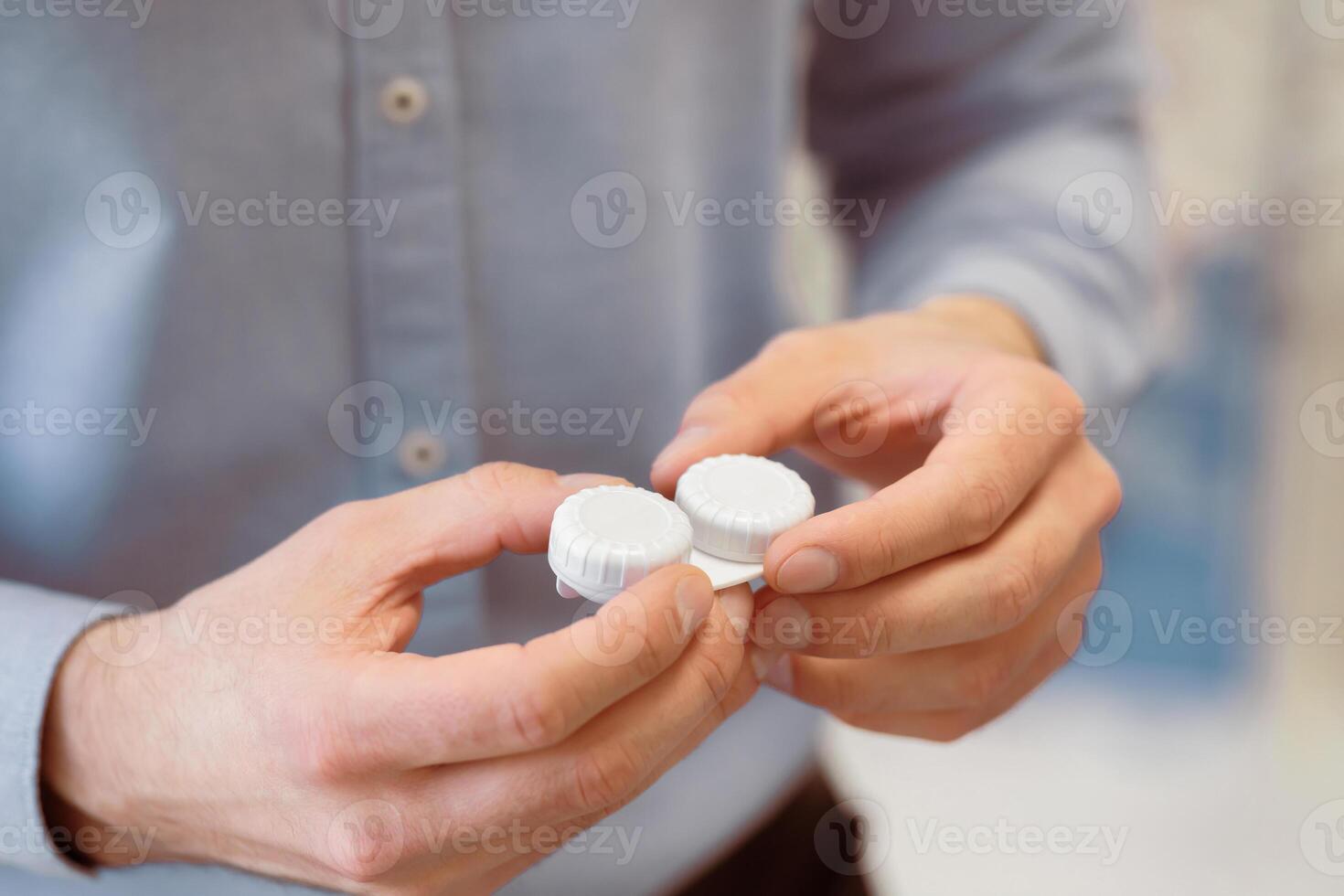 Close up of unrecognizable man holding contact eye lenses container, selective focus photo