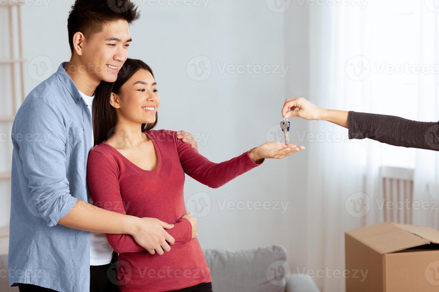Own House Concept. Unrecognizable female agent giving keys to smiling asian couple, empty space photo