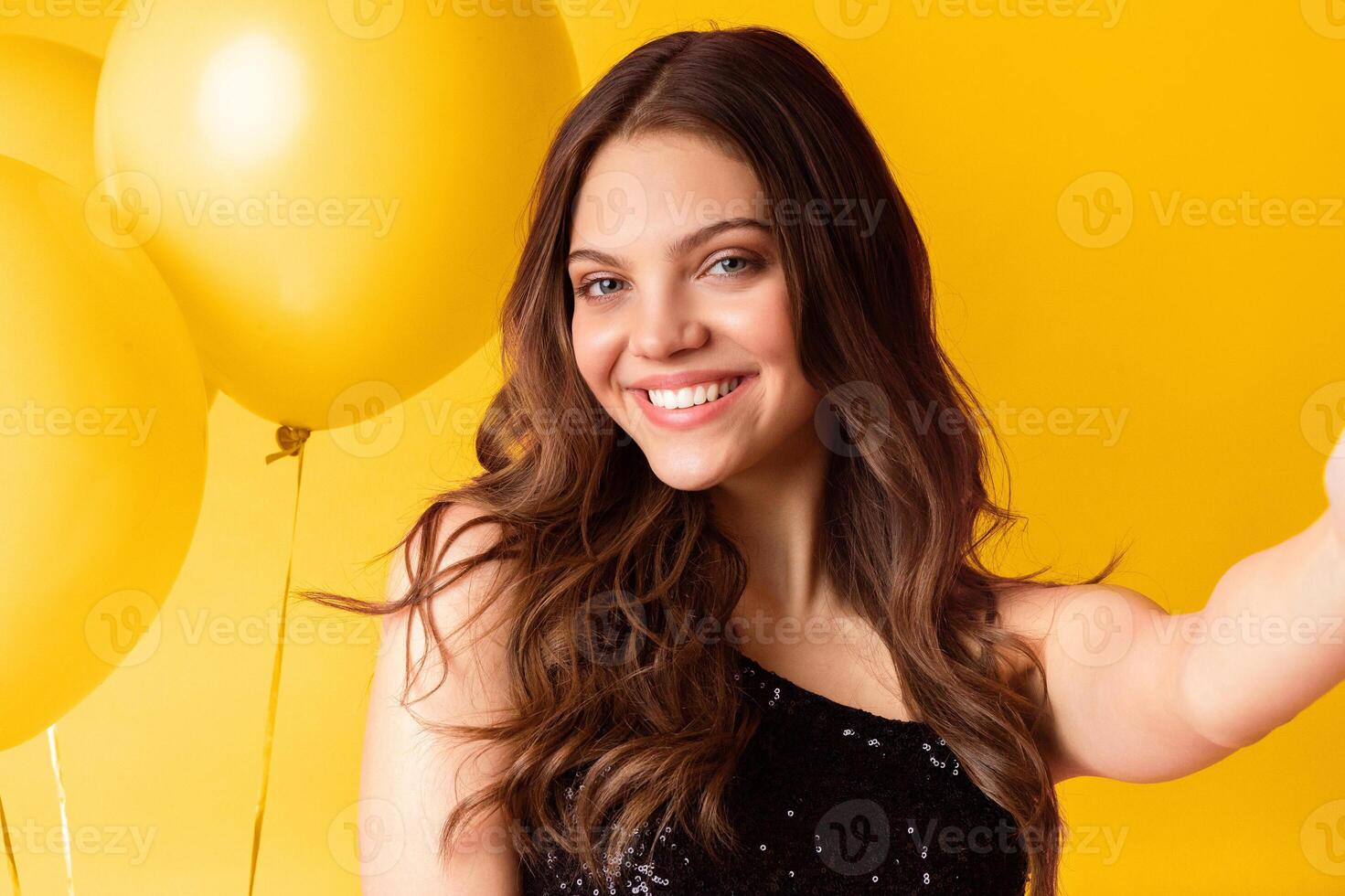 Lady Party. Selfie portrait of young pretty woman smiling at camera with big colorful balloons on background, capturing self-portrait at event photo