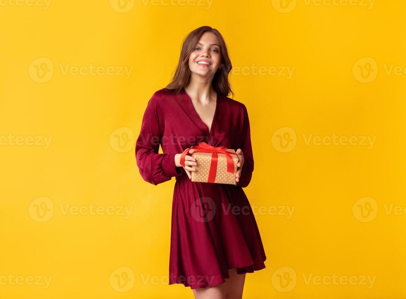 Pleasant Gift. Joyful Young Woman Holding Present Box In Hands And Posing At Camera On Colorful Background In Studio, Empty Space photo