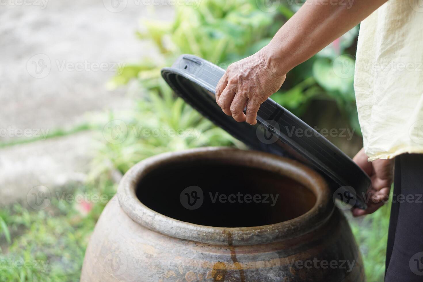 Closeup hands hold lid to cover water jar to protect from mosquitoes to breed inside or other insects or dust go into water. Concept, campaign to stop mosquitoes cycle to lay eggs in water container photo