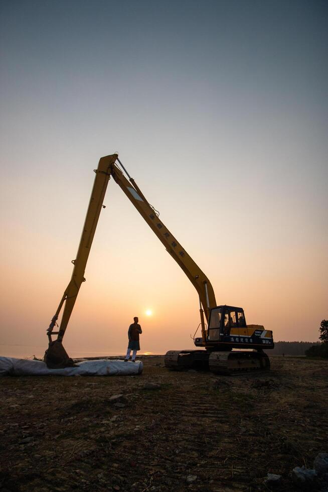 a man standing in front of a large excavator photo