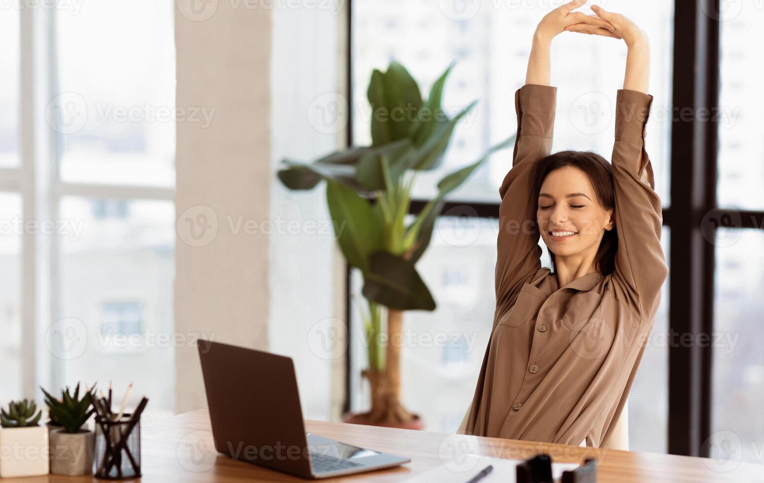 Stress Relief. Smiling young student is relaxing at workspace and stretching her body, copyspace photo