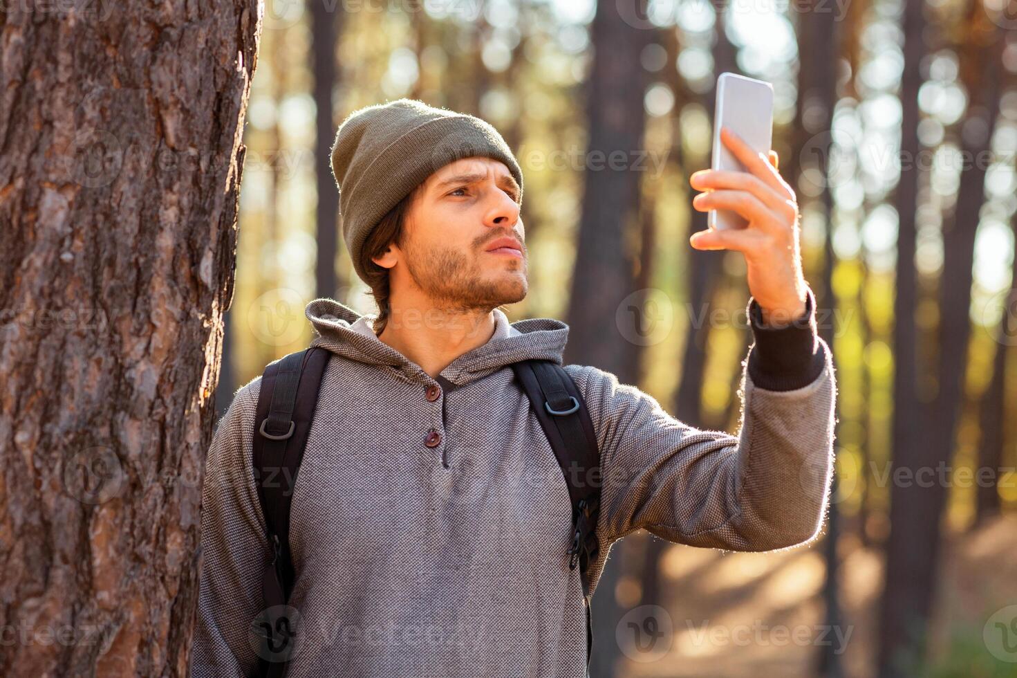 Stay connected. Young guy checking for mobile internet in the middle of autumn forest, hiking alone, copy space photo